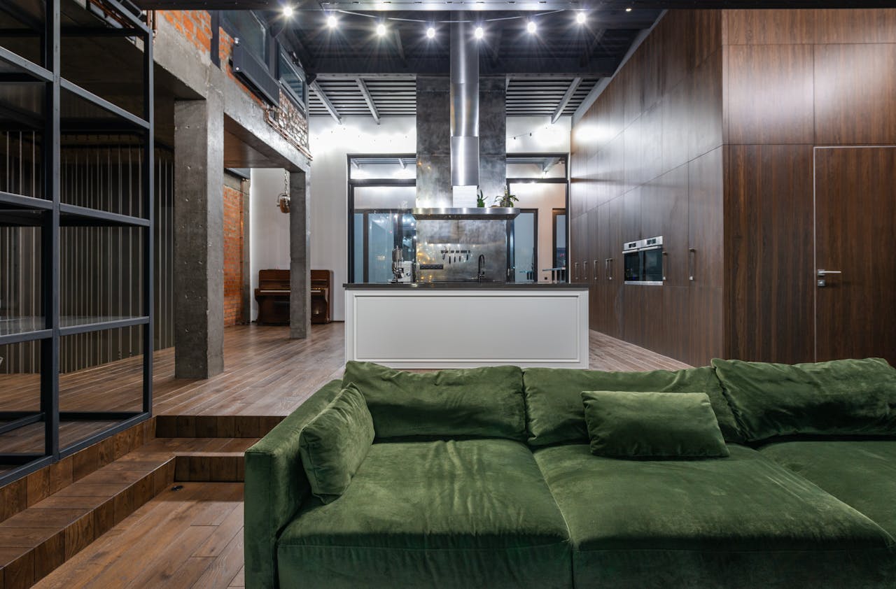 Comfortable green sofa placed in living room against kitchen zone in contemporary apartment